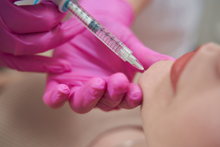Elegant female is receiving beauty procedure into the chin in salon